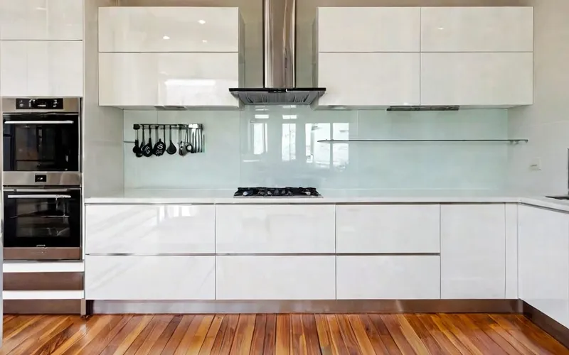 modern kitchen with white gloss cabinets, T-bar handles, and stainless steel appliances