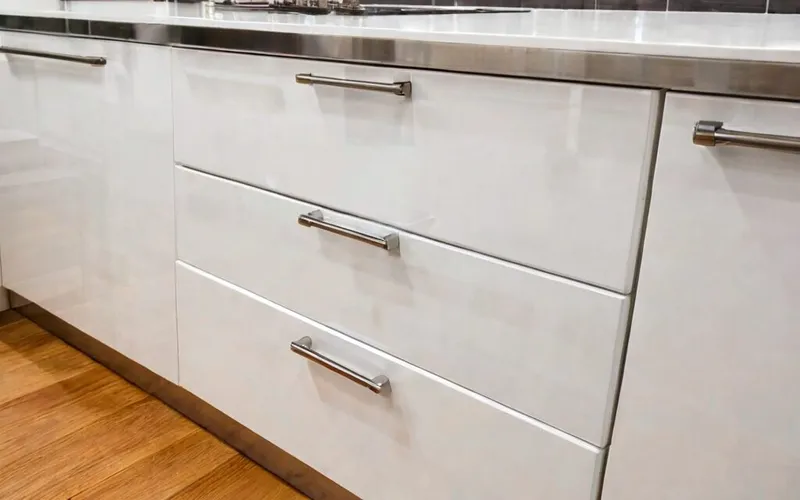 close-up of T-bar handle and gloss white cabinet door