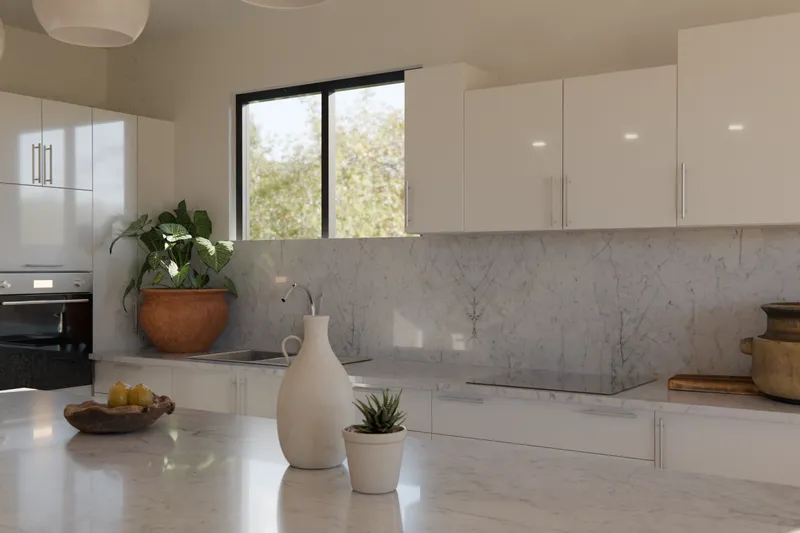 An open-plan gloss white kitchen with an island bench, pendants and garden views
