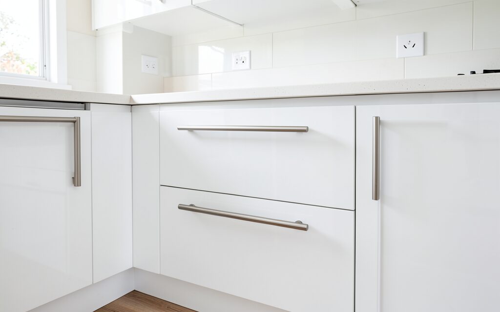 modern galley kitchen with white gloss cabinets and T-bar handles